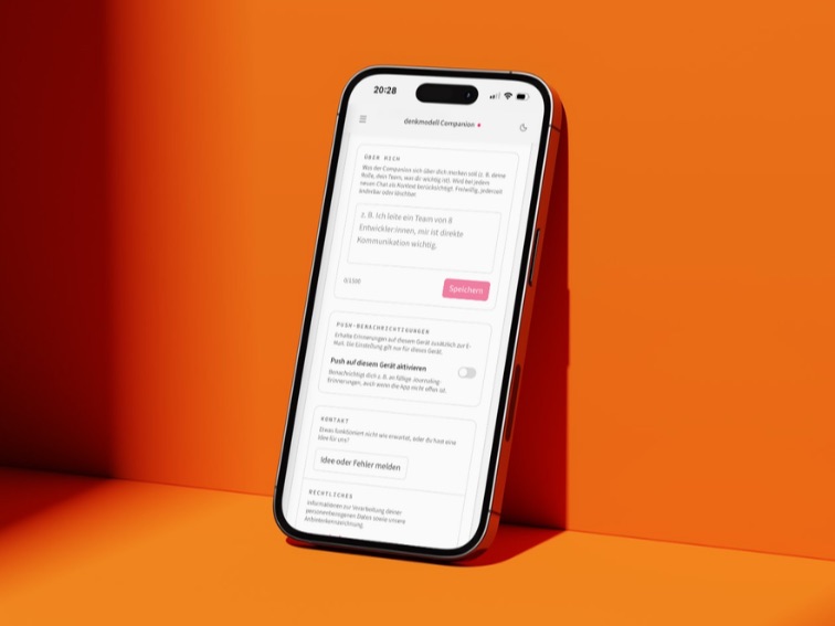 Smartphone mit dem denkmodell Companion vor einem warmen orangefarbenen Hintergrund.